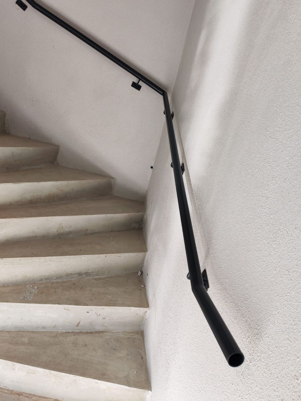 Cage d'escalier rénovée : béton peint et rampe métal