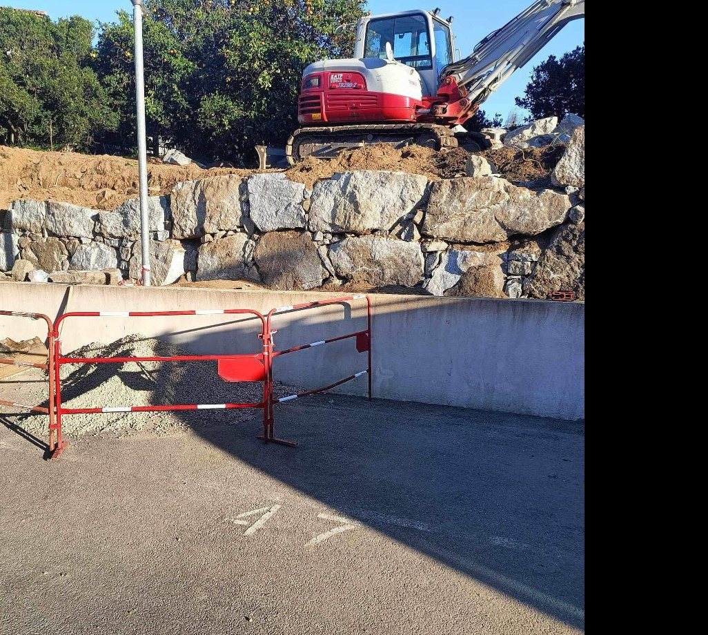 Pelle mécanique posant un enrochement au-dessus d'un mur technique, chantier Sud Travaux à Ajaccio