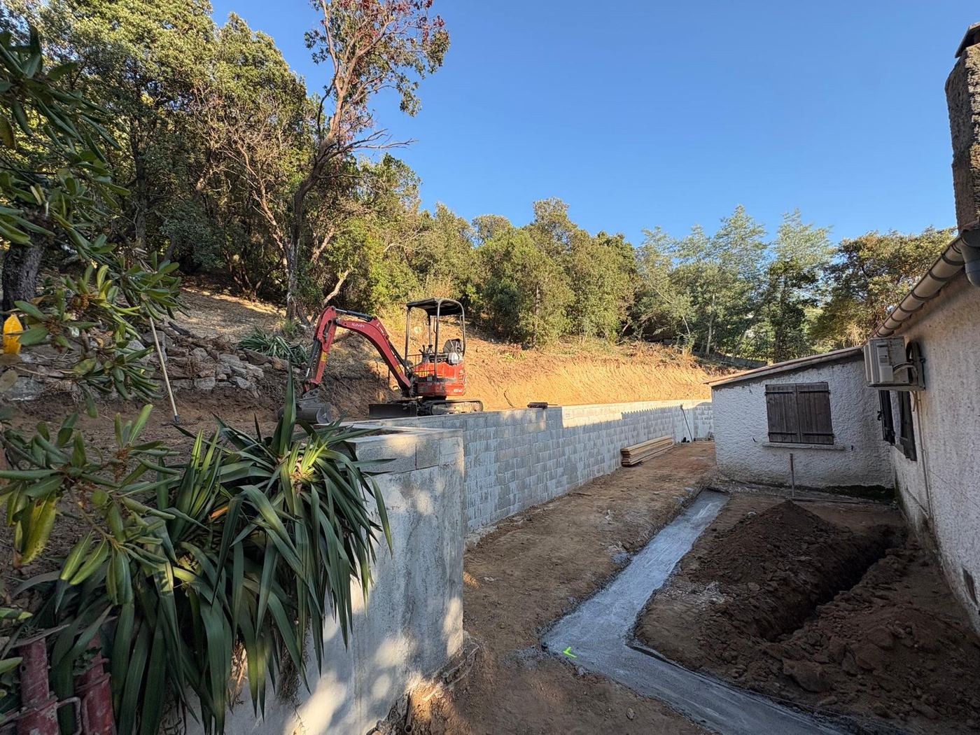 Le même espace après travaux : mur de soutènement, caniveau béton et talus retaillé